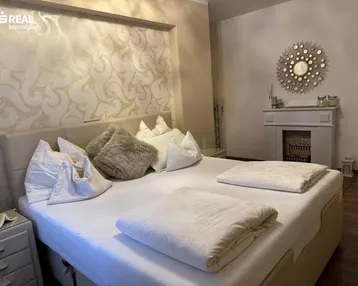 Geräumiges Schlafzimmer mit großem Bett, eleganter Tapete und einem dekorativen Kamin.
