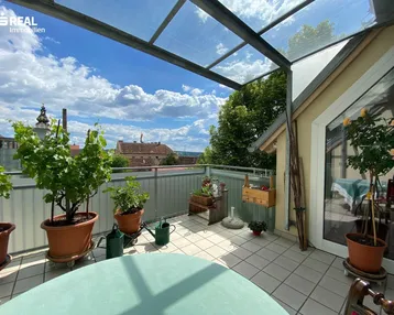 Geräumige Dachterrasse mit Glasüberdachung, Fliesenboden und weitem Blick ins Grüne.