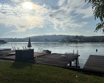 Malerischer Seeblick mit Holzstegen und Booten unter einem sonnigen Himmel.