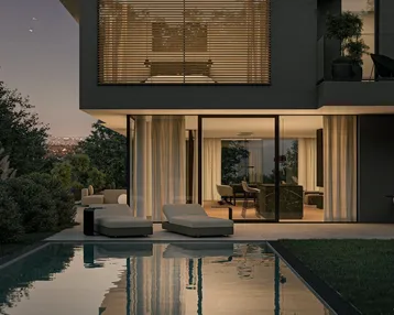 Elegante Poollandschaft mit Liegestühlen und Blick in den beleuchteten Wohnbereich am Abend.
