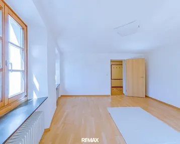 Helles, leeres Zimmer mit Holzfenstern und Parkettboden, bereit zur individuellen Gestaltung.
