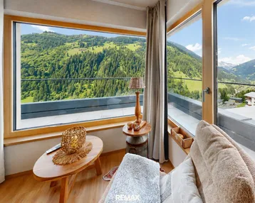 Gemütlicher Wohnbereich mit großen Fenstern und atemberaubendem Blick auf die umliegende Berglandschaft.