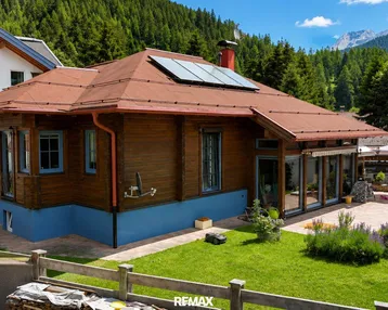 Charmantes Holzhaus mit rotem Dach, Solarpaneelen und gepflegtem Garten in alpiner Umgebung.
