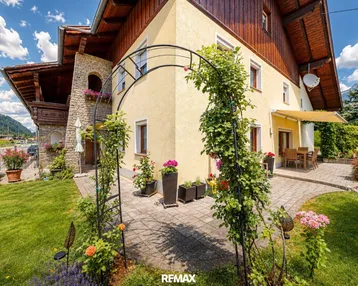 Charmantes Haus mit gepflegtem Garten, blühenden Pflanzen und einer gemütlichen Terrasse.