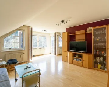 Helles Wohnzimmer mit Holzparkett, Dachschrägen und einem großen Mediamöbel in warmen Holztönen.
