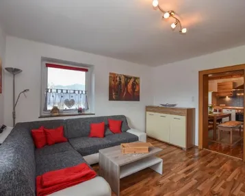 Helles Wohnzimmer mit gemütlichem Ecksofa, Laminatboden und Blick ins Grüne.