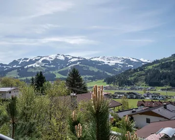 Panoramablick auf schneebedeckte Berge und die umliegende grüne Landschaft mit Häusern.