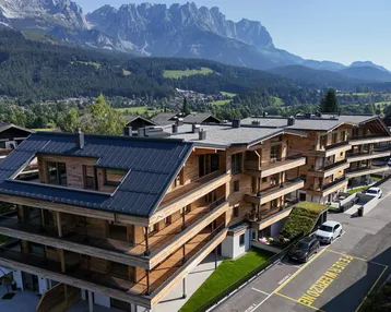 Modernes Mehrfamilienhaus in alpiner Umgebung mit Holzelementen und Bergblick.