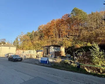 Ländliche Szene mit einem kleinen Gebäude, umgeben von Herbstbäumen und einer Straße.