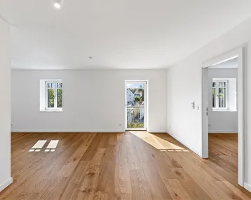 Heller Wohnbereich mit neuem Parkettboden, weißen Wänden und Zugang zu einem französischen Balkon.