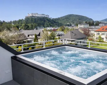 Dachterrasse mit Whirlpool und Panoramablick auf die Stadt und die umliegenden Berge.