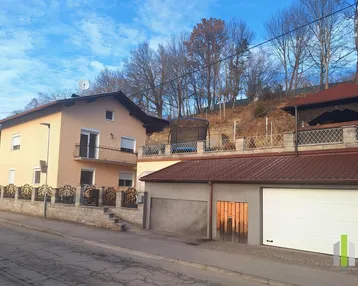 Ansicht des Hauses und der Garage von der Straße mit einem Trampolin im oberen Gartenbereich.