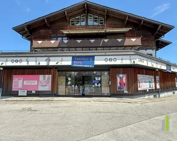 Geschäftsgebäude mit traditioneller Holzfassade im Obergeschoss und moderner Ladenfront im Erdgeschoss.