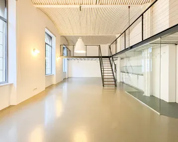 Heller, offener Loft-Wohnbereich mit gewölbter Decke und Blick auf die Stadt durch große Fenster.