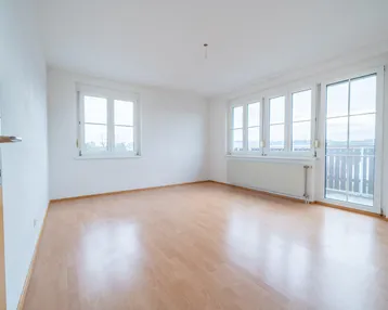 Helles, leeres Zimmer mit Laminatboden und Zugang zu einem Balkon, ideal für individuelle Gestaltung.