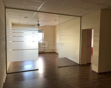 Heller Büroraum mit Glasabtrennungen und Deckenventilator, ausgestattet mit Laminatboden.