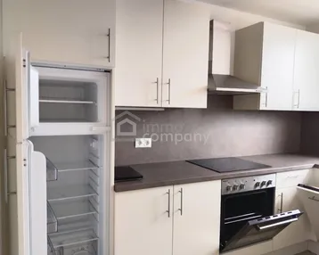 Helle Einbauküche mit weißen Schränken, Induktionskochfeld und integriertem Backofen.