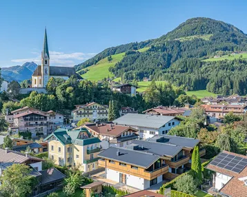 Panoramablick auf ein malerisches Dorf in den Bergen mit traditionellen Häusern und einer Kirche.
