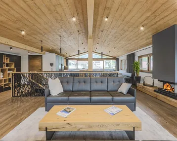 Heller Wohnbereich mit Kamin, Holzbalkendecke und bequemen Ledersofas in modernem Design.