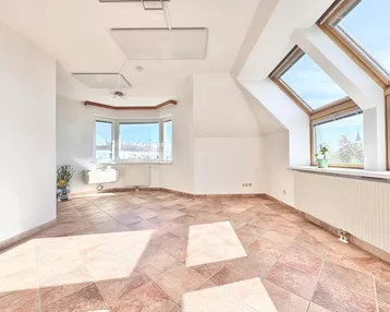 Helles Dachzimmer mit Fliesenboden, Erkerfenster und Dachfenstern, ideal als Wohnraum.