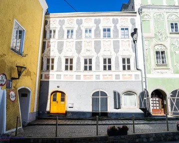 Historische Fassade eines Gebäudes mit kunstvollen Verzierungen und einer leuchtend gelben Eingangstür.