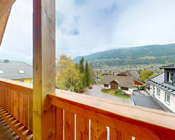 Geräumiger Holzbalkon mit weitem Blick auf die umliegende Berglandschaft.