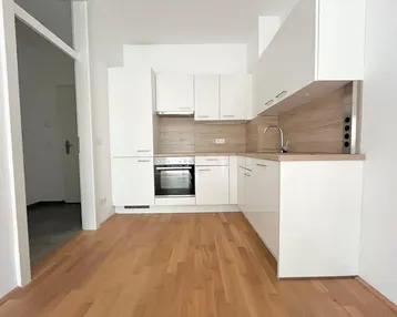 Moderne Einbauküche in Weiß mit Holzdetails, ausgestattet mit Backofen und Kochfeld, ideal für den Erstbezug.