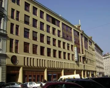 Großes Gebäude mit moderner Architektur, vielen Fenstern und einer belebten Straße davor.