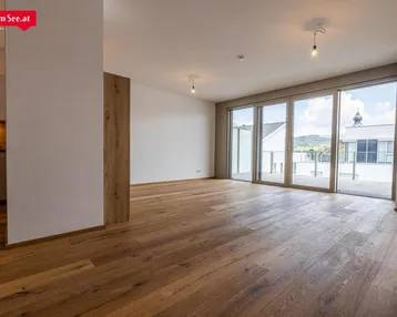 Heller Wohnbereich mit Holzboden und Zugang zu einer großen Terrasse mit Bergblick.