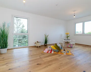 Kinderfreundliches Zimmer mit Holzboden, großen Fenstern und Blick ins Grüne.