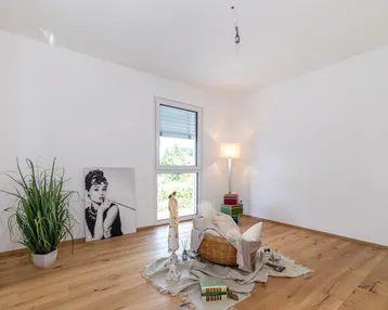 Helles Zimmer mit Holzboden, großem Fenster und moderner Dekoration mit Pflanzen und Kunst.