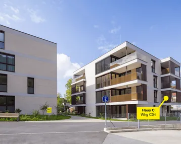 Moderne Mehrfamilienhäuser mit Balkonen und zeitgenössischer Architektur unter blauem Himmel.