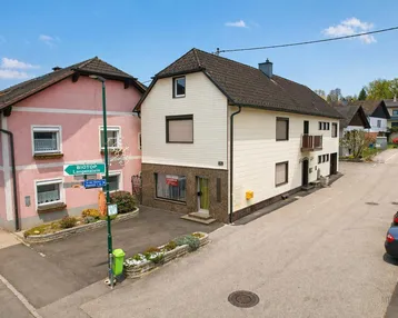 Luftaufnahme zweier Wohnhäuser mit Satteldächern und einer ruhigen Wohnstraße.