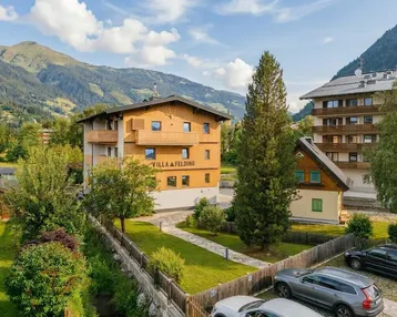 Modernes Gebäude mit Holzfassade und Balkonen in einer malerischen Berglandschaft.