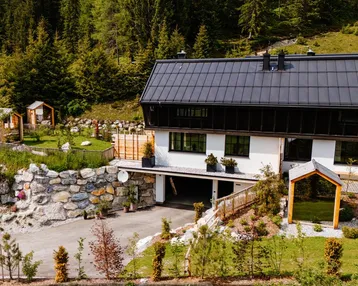 Modernes Haus in alpiner Umgebung mit Zufahrt und gepflegtem Gartenbereich.