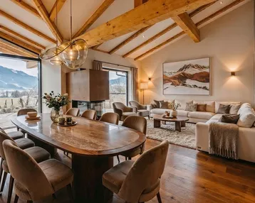 Großzügiger Wohn-Essbereich mit hohen Decken, Holzbalken, Kamin und Panoramablick auf die Berge.