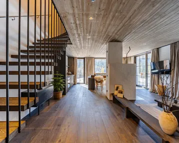 Modernes Interieur mit Holzfußboden, offener Treppe und Blick auf die Berge.