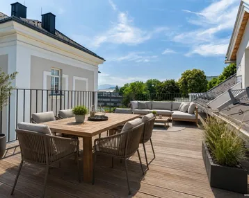 Große Dachterrasse mit Ess- und Lounge-Bereich, Holzboden und weitem Blick auf die Umgebung.