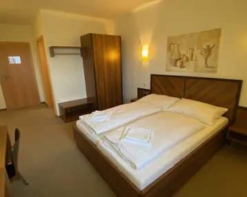 Gemütliches Schlafzimmer mit Doppelbett, Holzmöbeln und indirekter Beleuchtung an den Wänden.