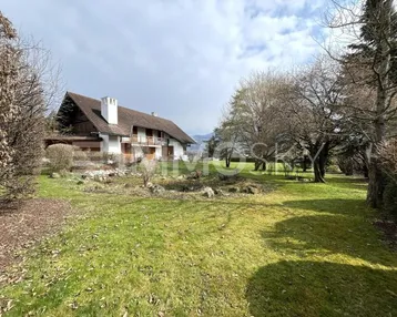 Großzügiges Anwesen mit weitläufigem Garten, umgeben von Bäumen und mit Blick auf das Wasser.