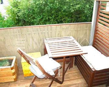 Gemütlicher Balkon mit Holzboden, Sitzgelegenheiten und grüner Bepflanzung für entspannte Stunden im Freien.