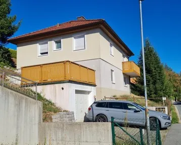 Ansicht des Hauses von der Straße mit Garage und Balkon im Vordergrund.