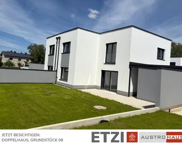 Modernes Doppelhaus mit weißer Fassade, grauen Akzenten und gepflegtem Rasen unter blauem Himmel.