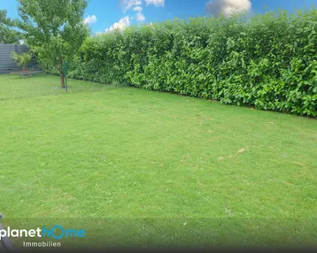 Gepflegter Rasenbereich im Garten mit einer hohen Hecke, die Privatsphäre bietet.