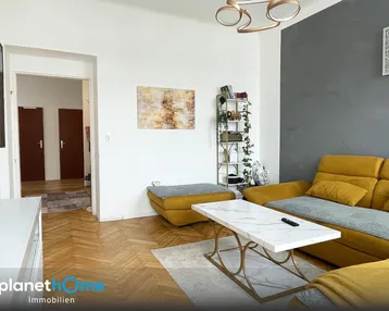 Helles Wohnzimmer mit gelbem Sofa, modernem Couchtisch und Blick in den Flur mit Parkettboden.