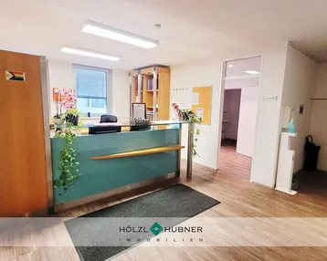 Empfangsbereich mit modernem Tresen, Pflanzen und Holzakzenten, der einen einladenden ersten Eindruck vermittelt.