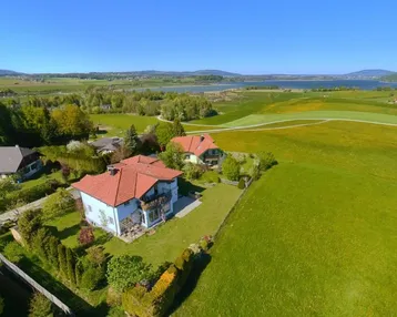 Luftaufnahme des Anwesens mit weitem Blick über die Landschaft und einen See.