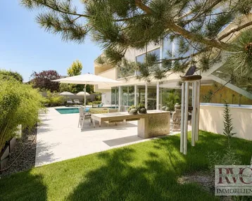 Großzügige Terrasse mit Essbereich, Sonnenschirm und Pool, umgeben von Grünflächen und Bäumen.