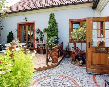 Gemütliche Terrasse mit Gartenmöbeln und Blumenbeeten, direkt am Haus gelegen.