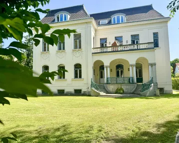 Klassische Villa mit Mansarddach, großzügigem Garten und repräsentativem Eingangsbereich.